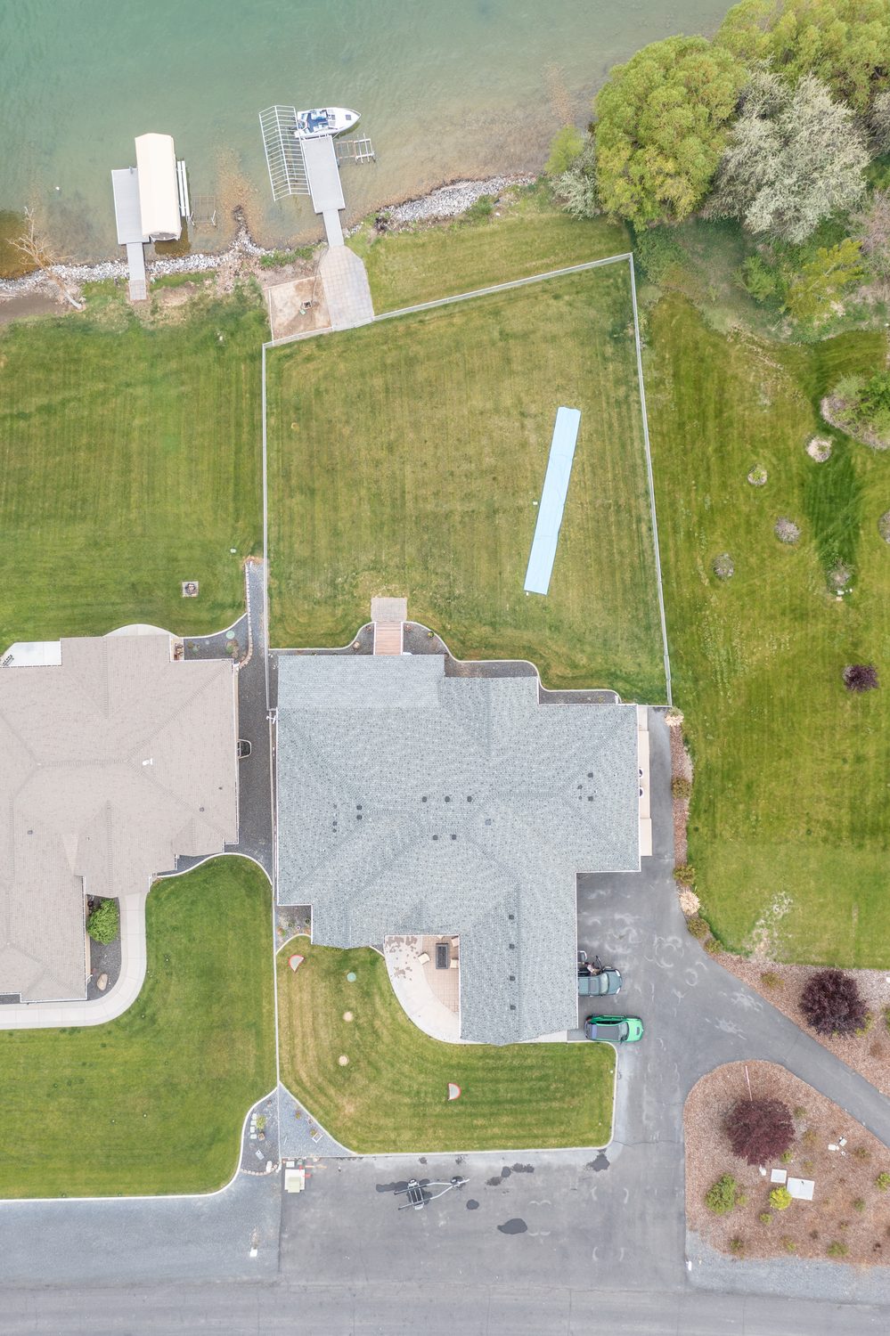 Drone view straight down: driveway, house, fenced yard, patio, dock and lifts